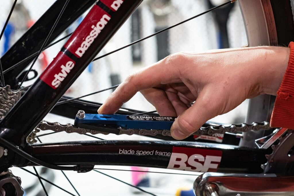 En person bruger et værktøj til at tjekke om en cykelkæde er slidt og skal skiftes