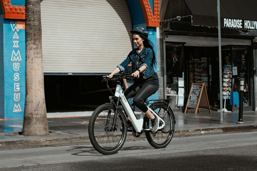 Kvinde i blå denim jakke køre på en hvid elcykel i byen ved dagslys