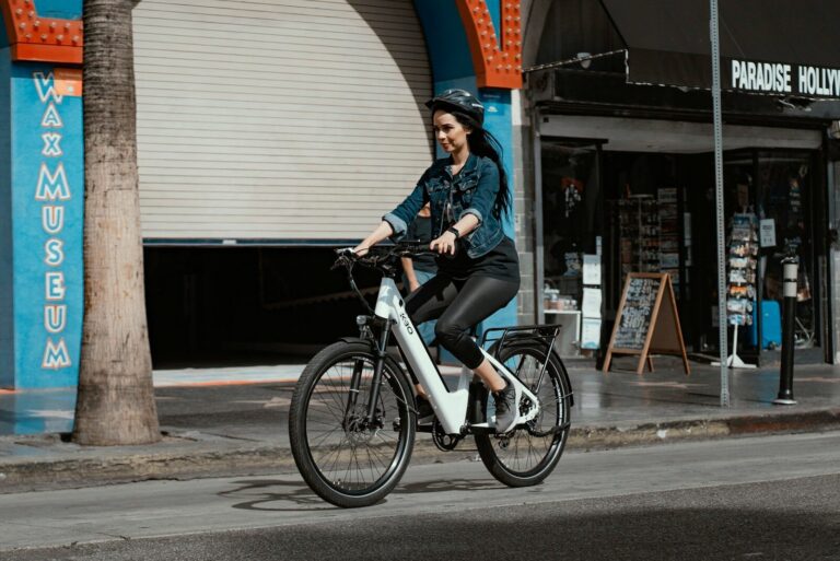 Kvinde i blå denim jakke køre på en hvid elcykel i byen ved dagslys