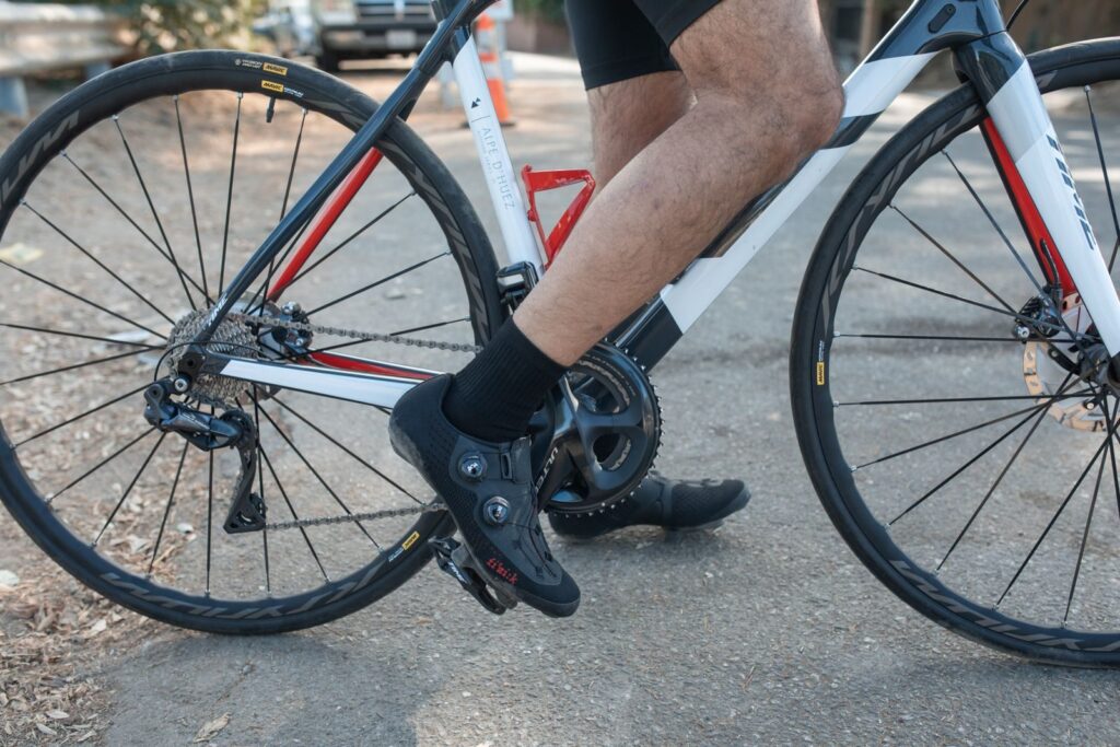 Cyclist riding a road bike wearing clipless shoes, showcasing sports gear and activity.