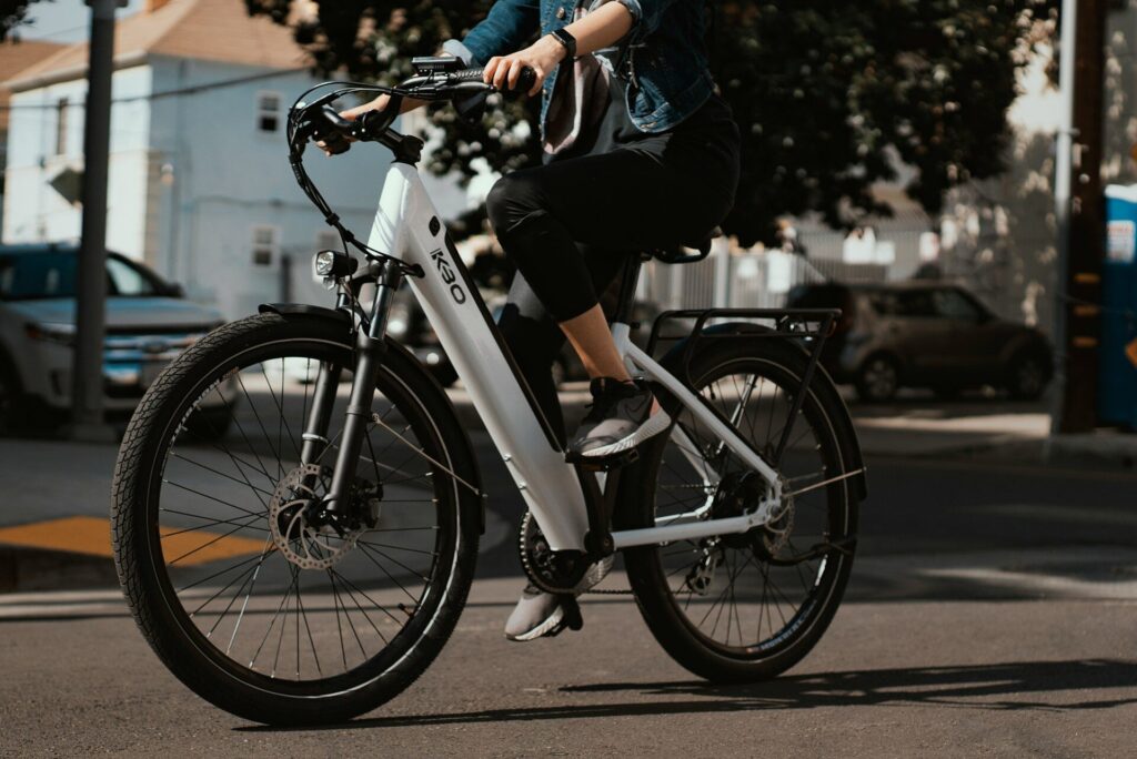 Mand cykler i byen på hvid og sort elcykel ved dagslys