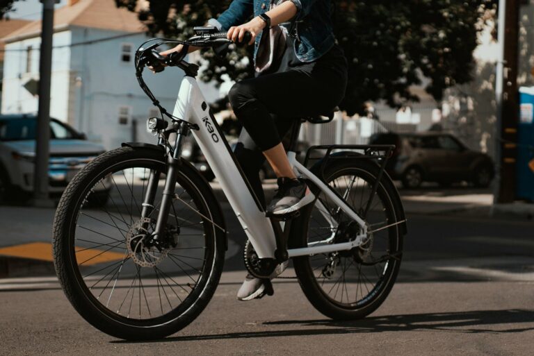 Mand cykler i byen på hvid og sort elcykel ved dagslys