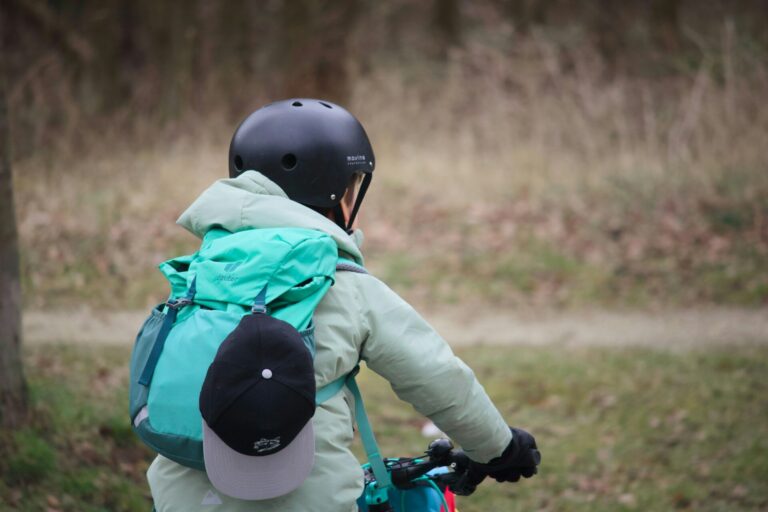 Barn med cykelhjelm og rygsæk cykler på vej til skole
