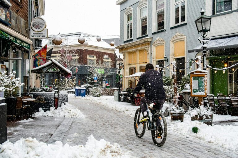En person cykler gennem en by i snevejr om vinteren